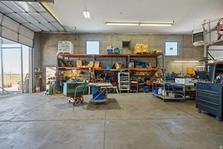 Spacious industrial interior featuring a concrete floor, high ceilings with fluorescent lighting, and block wall construction