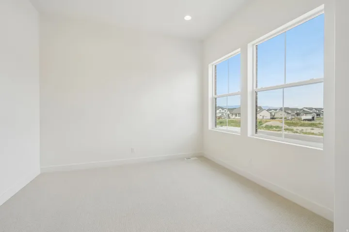Bright interior space featuring two large sash windows, recessed ceiling lighting, light-toned carpeting, and crisp white baseboards