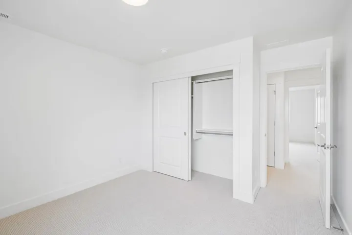 Neutral carpeted room featuring a double-sliding door closet with integrated shelving and hanging rod