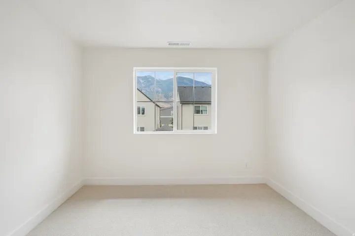 Bright room featuring a single window, light-colored carpeting, white baseboards, and a neutral wall finish