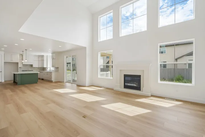 Vaulted great room featuring wood-finish flooring, a cast stone fireplace, and tall windows