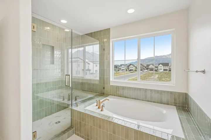 Contemporary bathroom featuring an integrated soaking tub with brass fixtures and a large window
