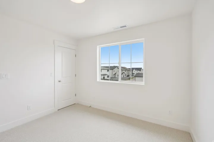 Bright room featuring a large window, white trim, recessed lighting, and light-colored carpeting