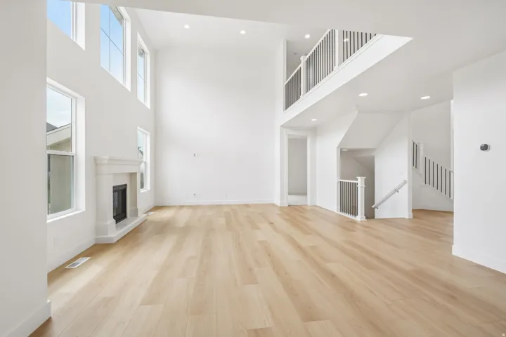 Spacious living area featuring high ceilings, wood-finish flooring, and a decorative fireplace