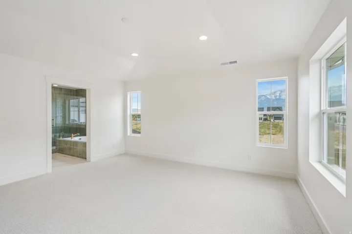 Spacious room featuring vaulted ceilings, recessed lighting, and soft carpet flooring