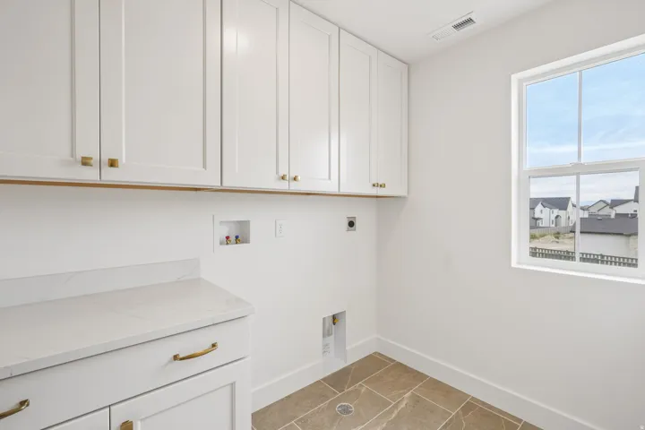 White shaker cabinetry with gold-tone hardware, white countertop, and tiled flooring