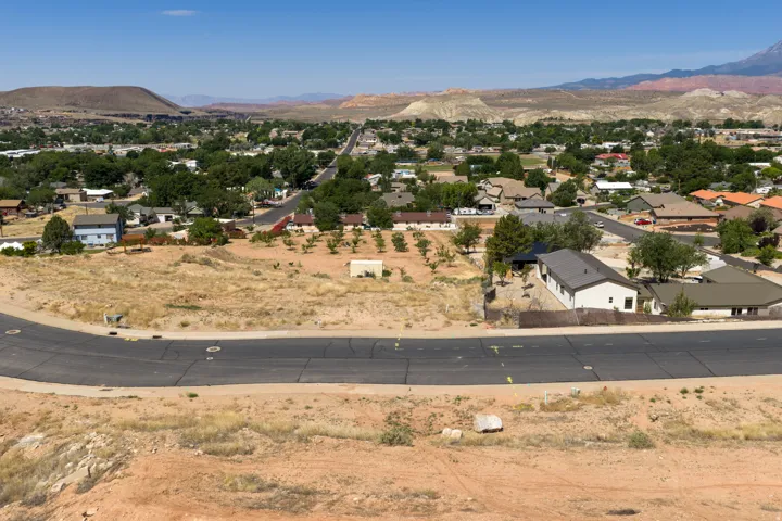 Expansive vacant lot featuring an asphalt street frontage and scattered natural vegetation