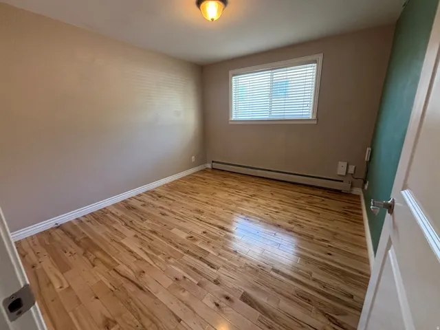 Bright room featuring wood-finish flooring, neutral wall tones, and a window with horizontal blinds