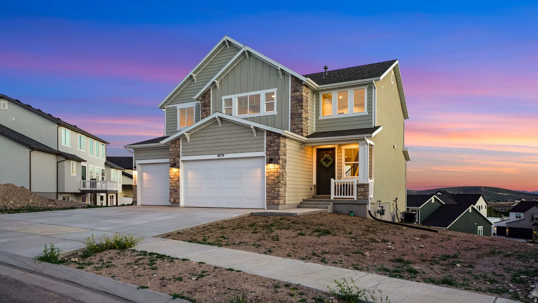 Two-story residence featuring light green siding and stone accents