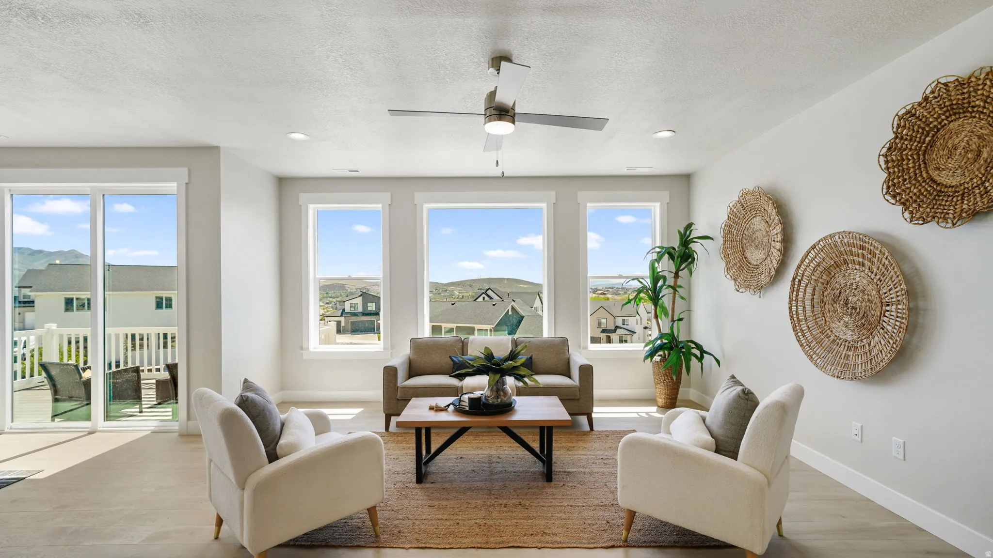 Living area featuring multiple large windows, wood-finish flooring, a ceiling fan with integrated lighting, and recessed overhead lighting