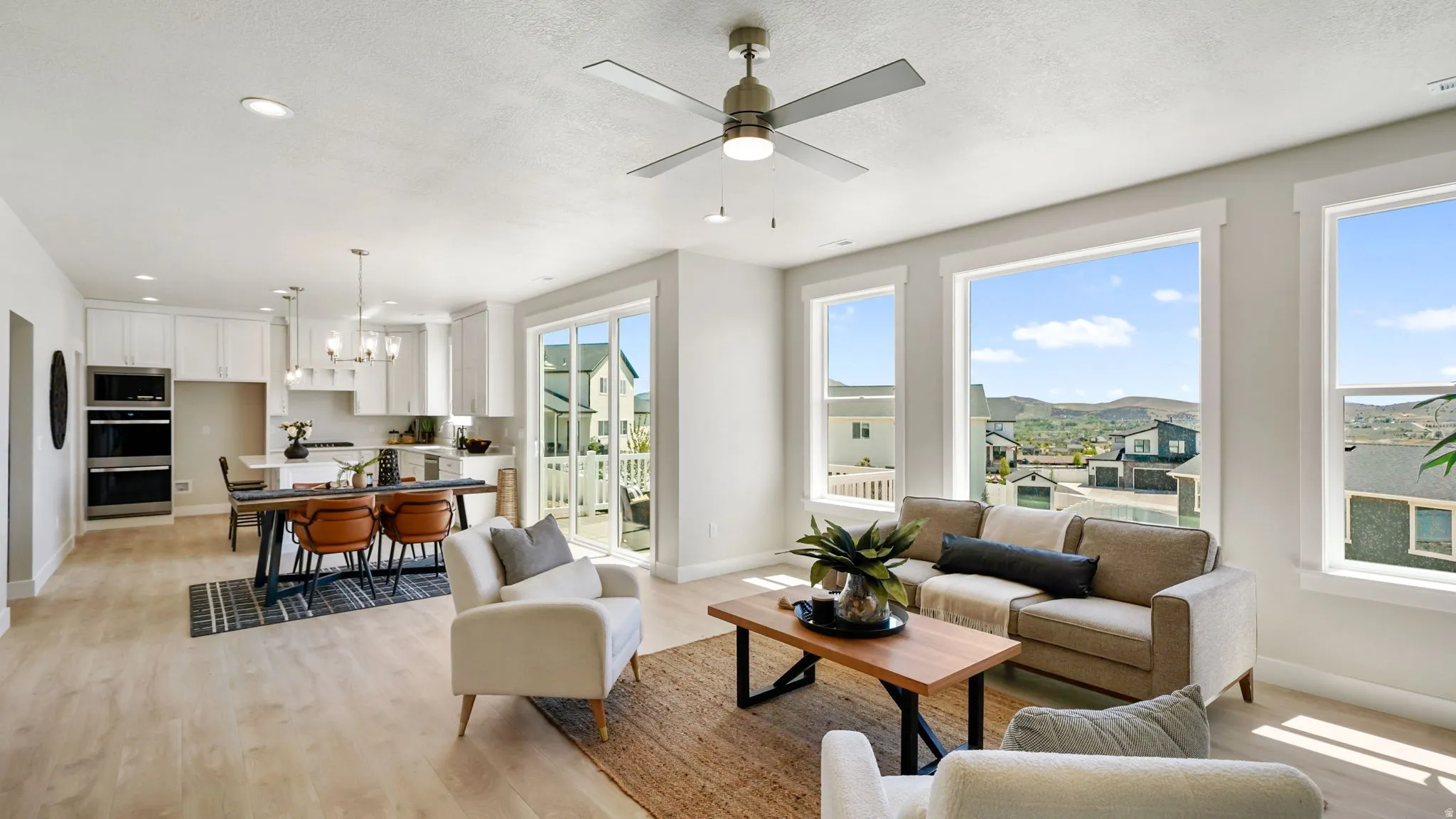 Open-concept living area with light wood-finish flooring, recessed lighting, and a contemporary ceiling fan