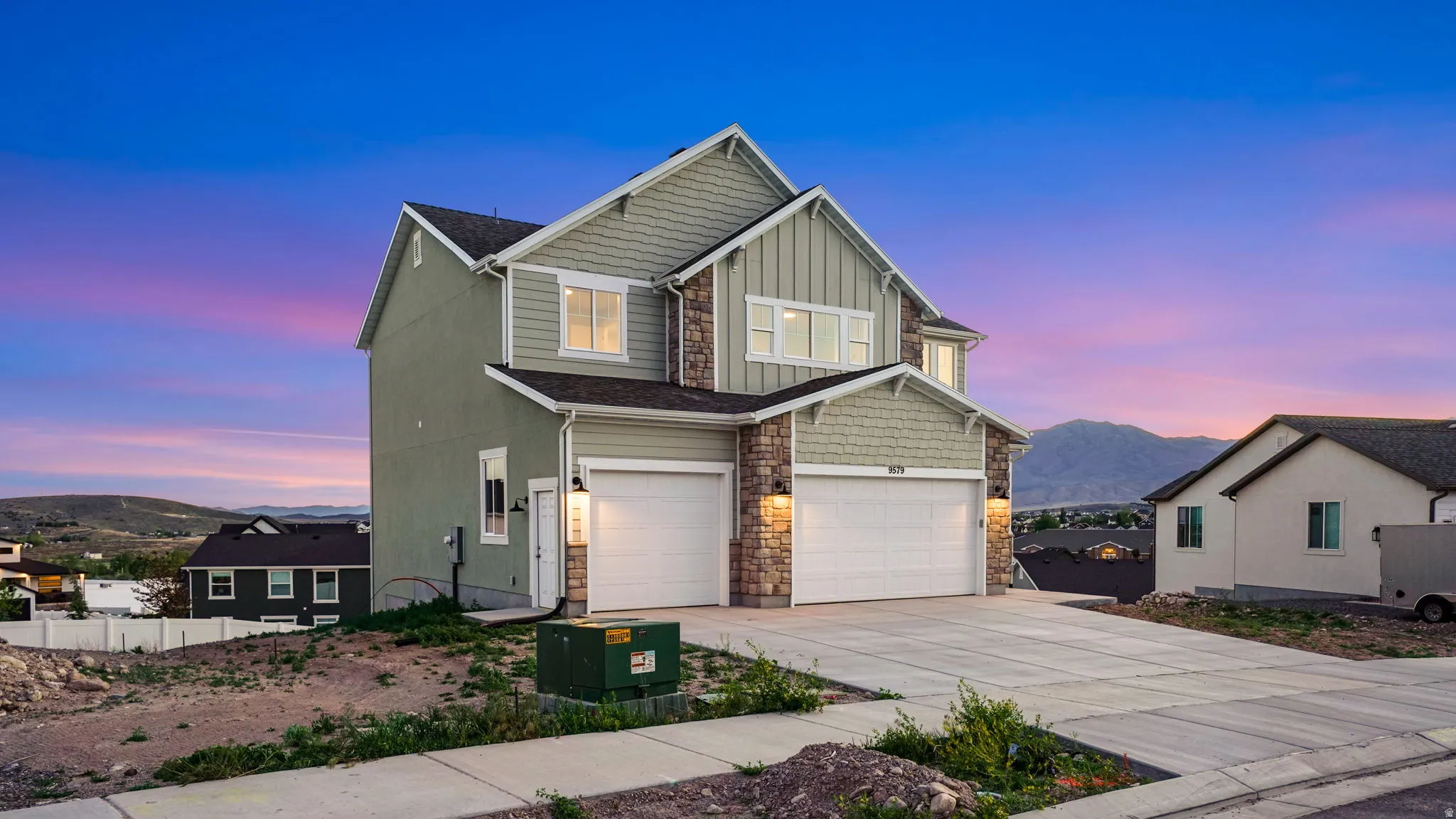 Two-story residence featuring light green siding and stone veneer accents