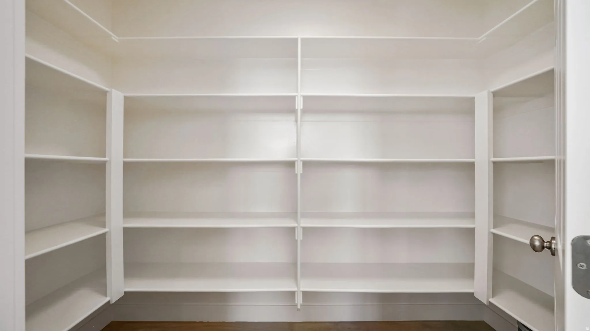 Expansive pantry featuring multiple built-in white shelves, providing abundant storage capacity