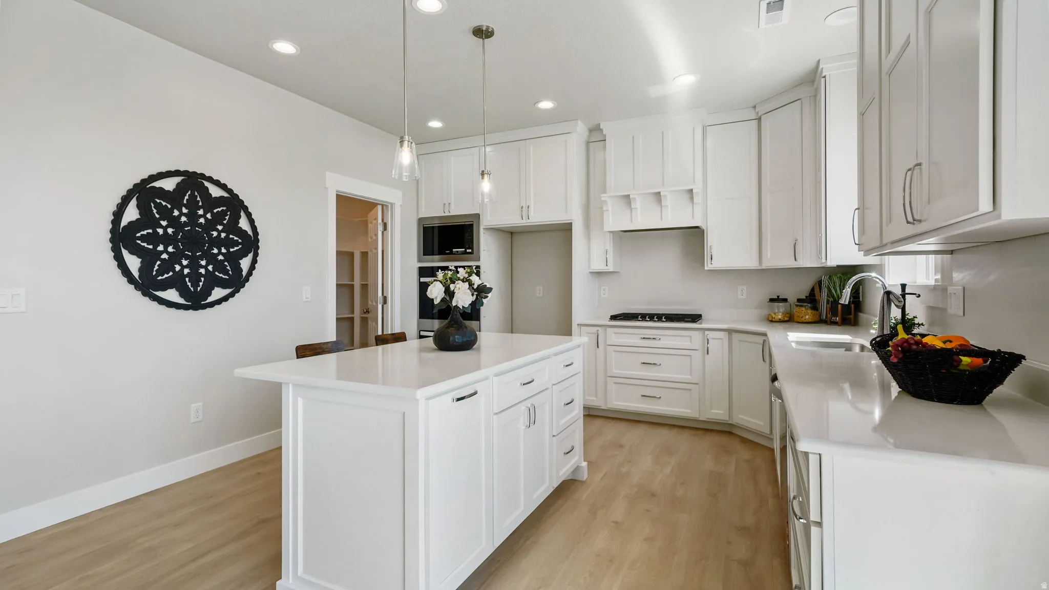 Modern kitchen featuring a central island with countertop seating, white cabinetry, integrated appliances, and recessed lighting