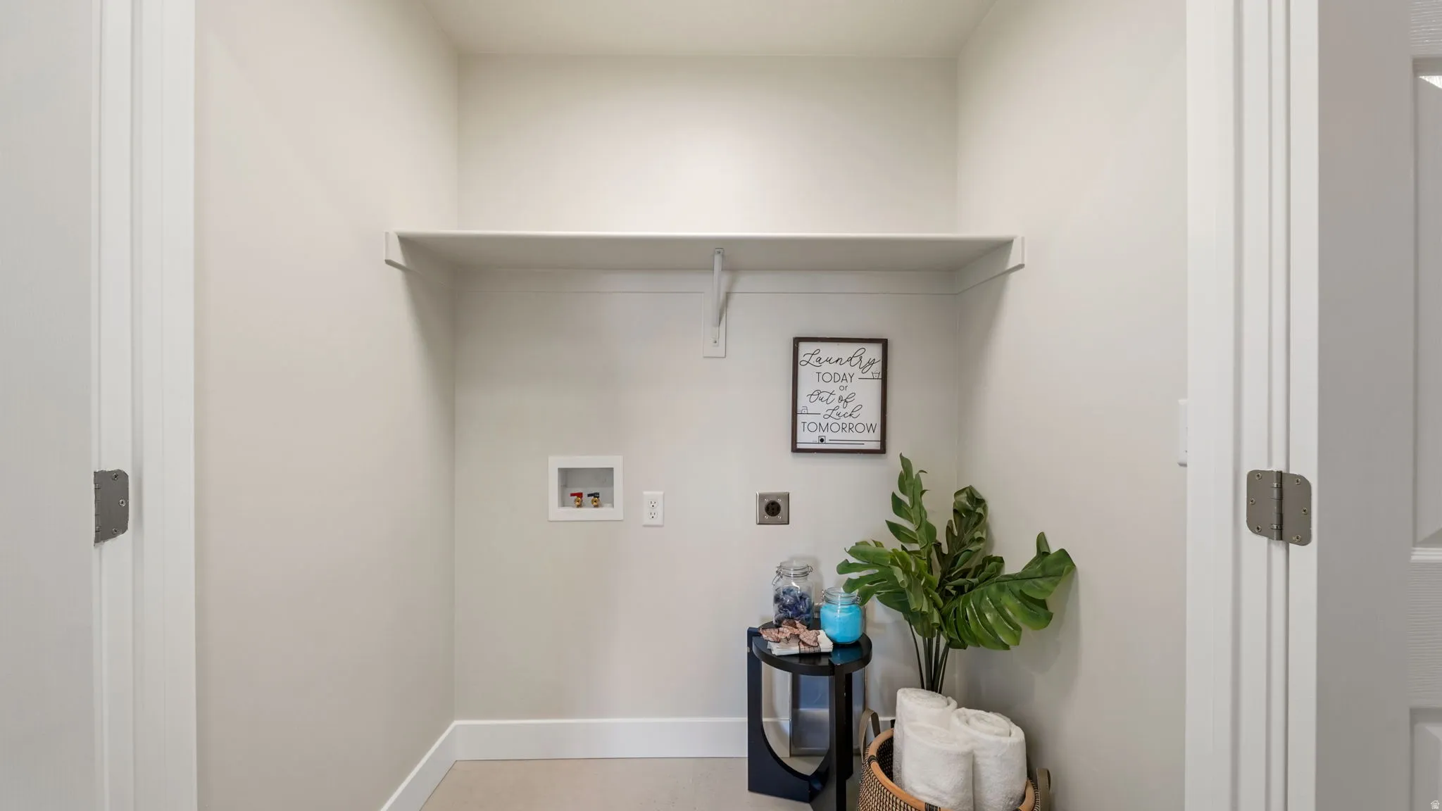 Dedicated laundry area featuring a built-in shelf, neutral wall tones, and utility hookups