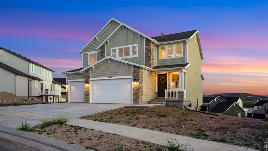 Two-story residence featuring light green siding and stone accents