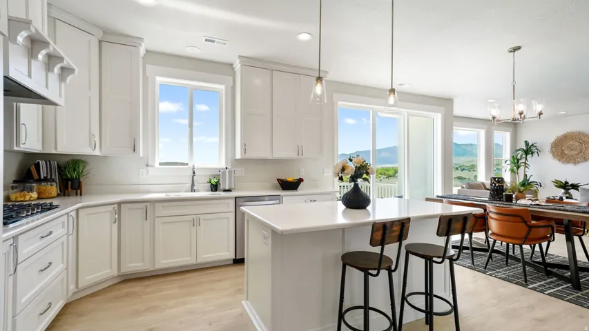 Spacious kitchen featuring white shaker-style cabinetry, light countertops, and an integrated island with pendant lighting