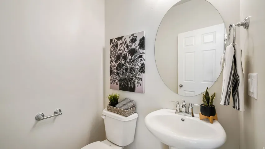 Pedestal sink with chrome fixtures, round wall mirror, and white paneled door