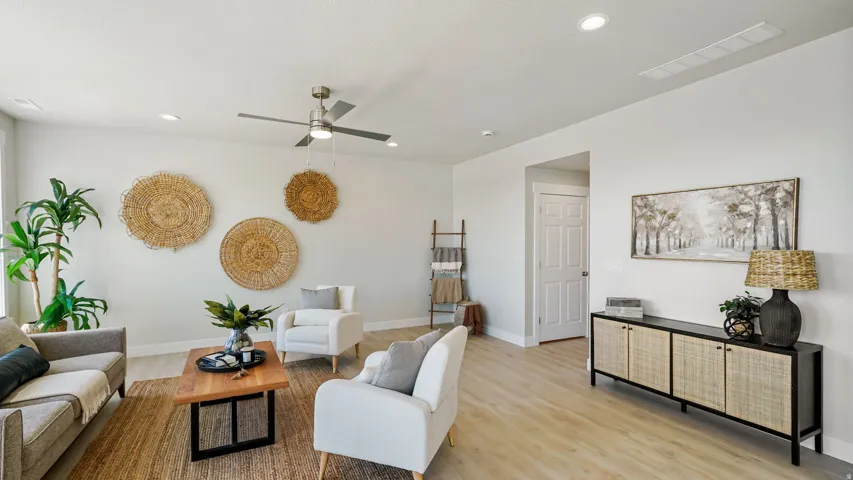 Bright living space featuring light wood-finish flooring, recessed lighting, and a ceiling fan