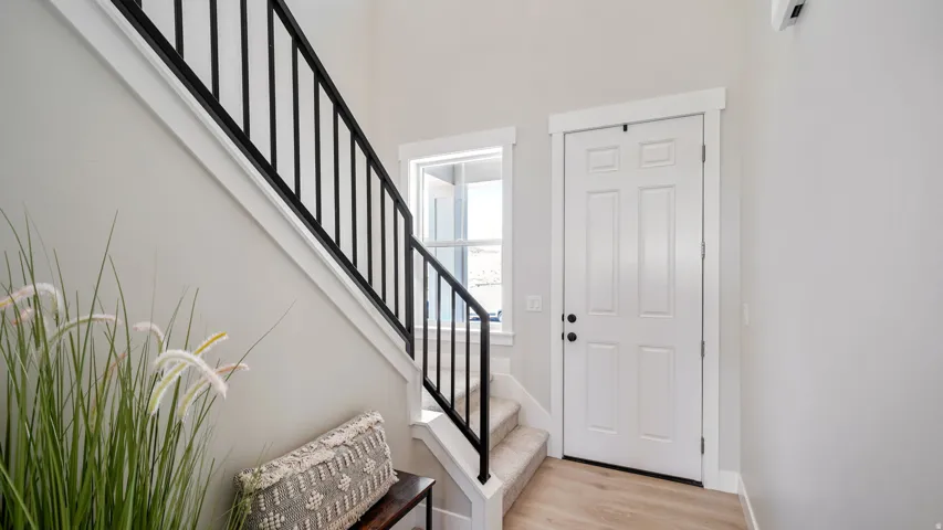 Interior entryway featuring a staircase with black metal balusters and a paneled white door