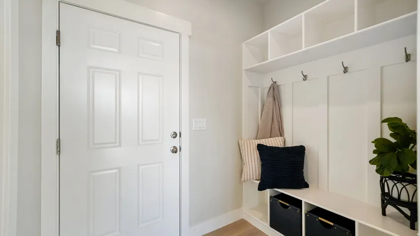 Entryway featuring a paneled door with polished hardware, built-in mudroom storage, an integrated bench, and overhead shelving with cubbies