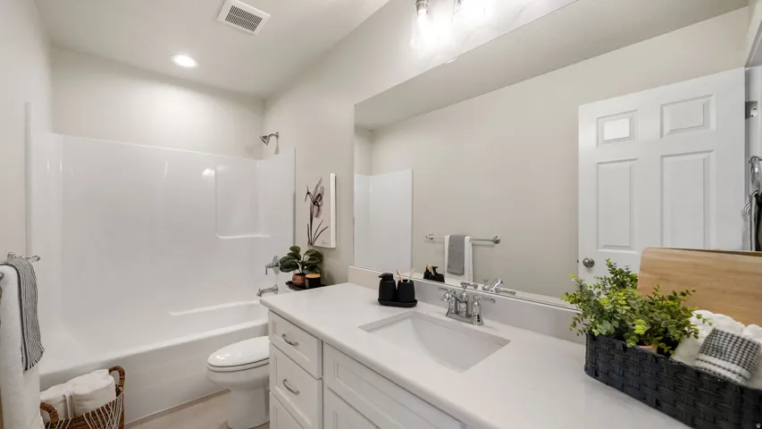 Bright bathroom featuring a white vanity with an integrated sink, polished chrome faucet, and expansive mirror