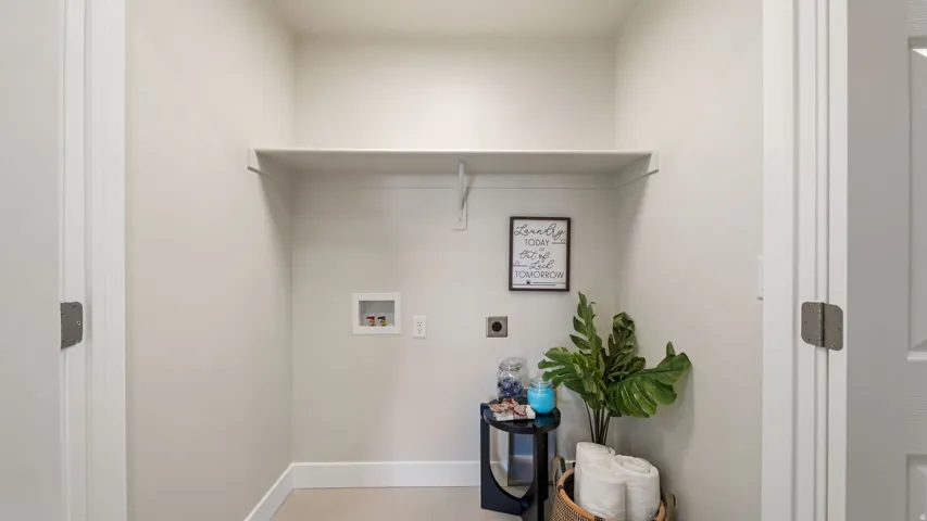 Dedicated laundry area featuring a built-in shelf, neutral wall tones, and utility hookups
