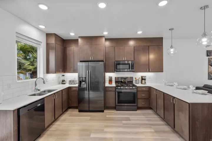 Kitchen featuring wood-finish flooring, white countertops, subway tile backsplash, recessed lighting, and stainless steel appliances