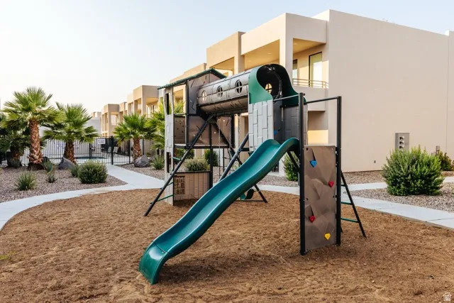 Community playground featuring a slide and climbing wall set in a sand base