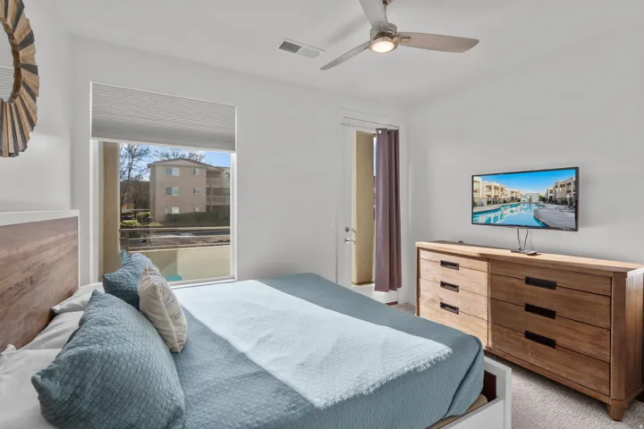Bedroom featuring a large window, a glass-paned door, and a ceiling fan with integrated lighting
