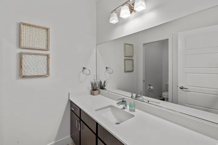 Spacious vanity with an integrated rectangular sink, expansive mirror, and dark wood-finish cabinetry