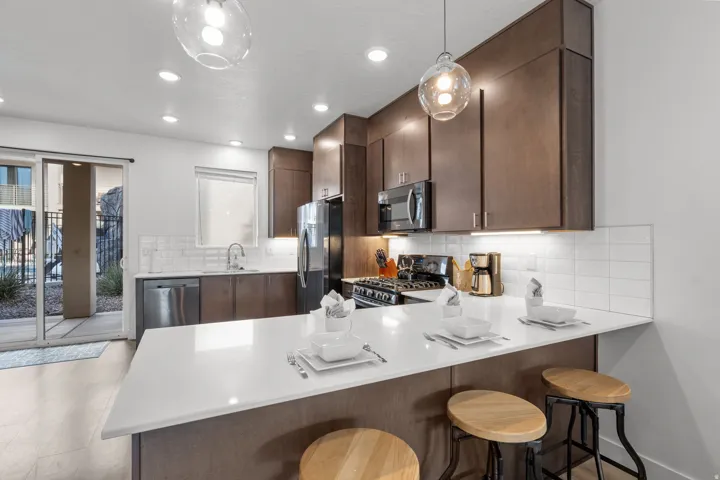 Modern kitchen featuring dark wood-finish cabinetry, stainless steel appliances, white subway tile backsplash, and a large white countertop island with seating