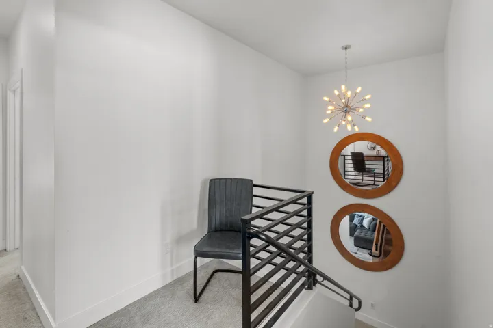 Staircase featuring contemporary metal railings, plush carpeting, and a modern sputnik chandelier
