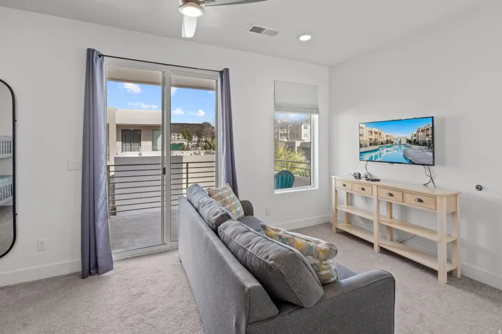 Carpeted interior space featuring a sliding glass door opening to a private balcony with horizontal railings
