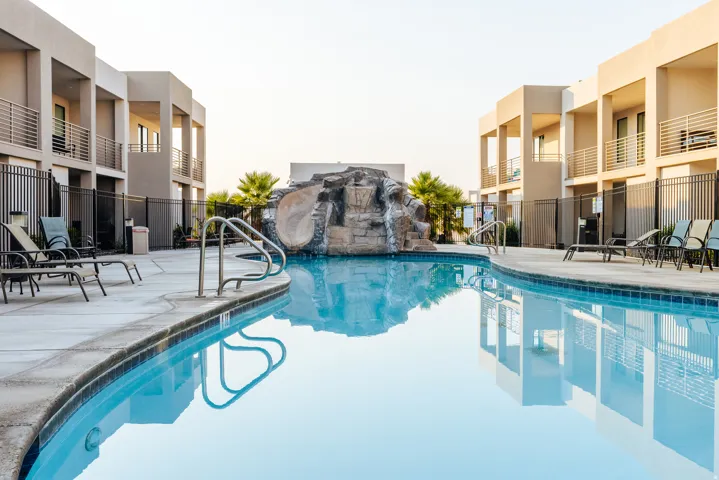 Expansive outdoor pool area featuring a curved swimming pool with integrated rock formation and waterslide