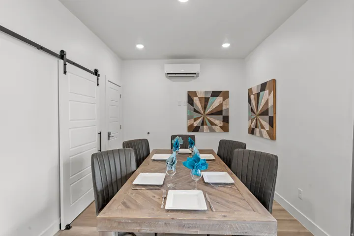 Dining area featuring a substantial wood-finish table, track lighting, and a modern barn door
