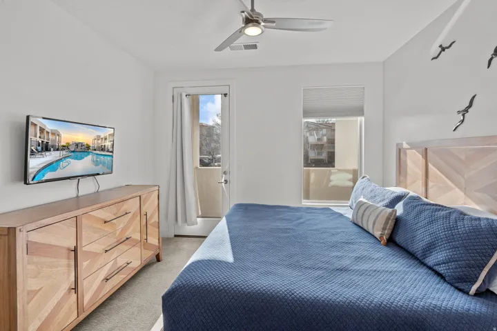 Bedroom featuring neutral wall tones, a ceiling fan with integrated lighting, and a private exterior door leading to an outdoor space
