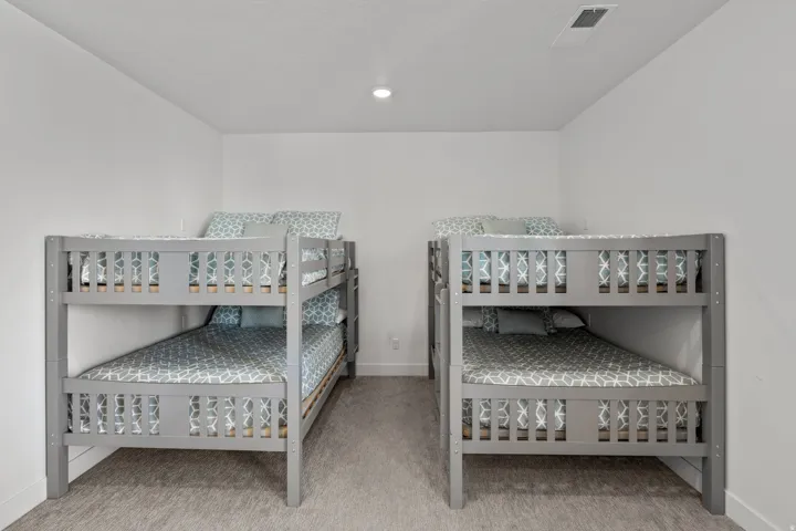 Bedroom featuring two wooden bunk beds with gray frames, white walls, recessed lighting, and carpeted flooring
