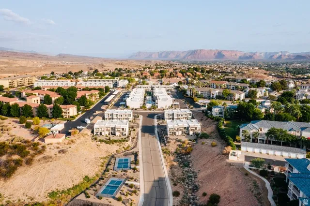 Aerial perspective featuring a residential community with multi-story buildings and red rock formations in the distance