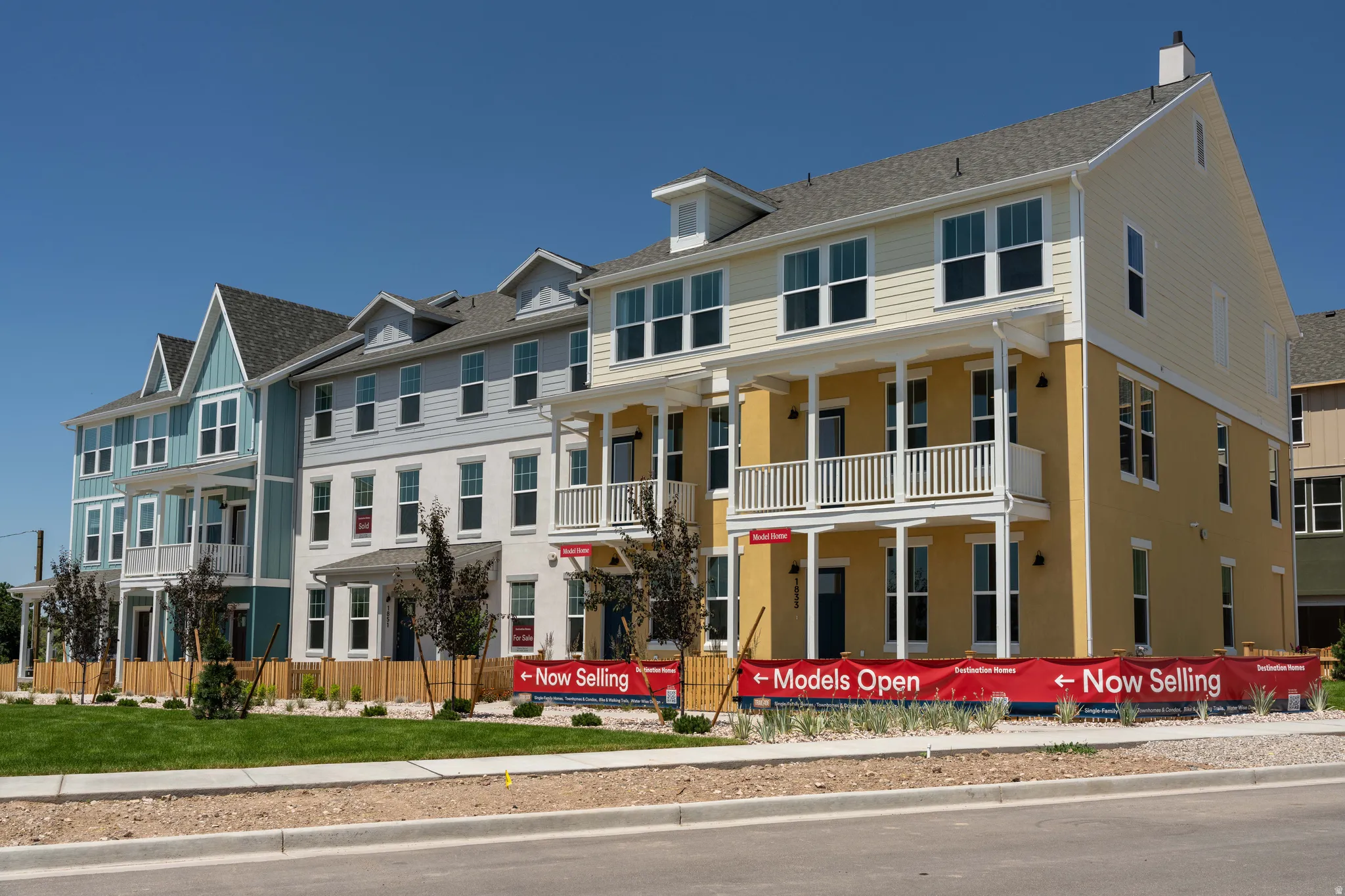 Newly constructed townhomes featuring multi-story designs, covered porches, and dormer windows