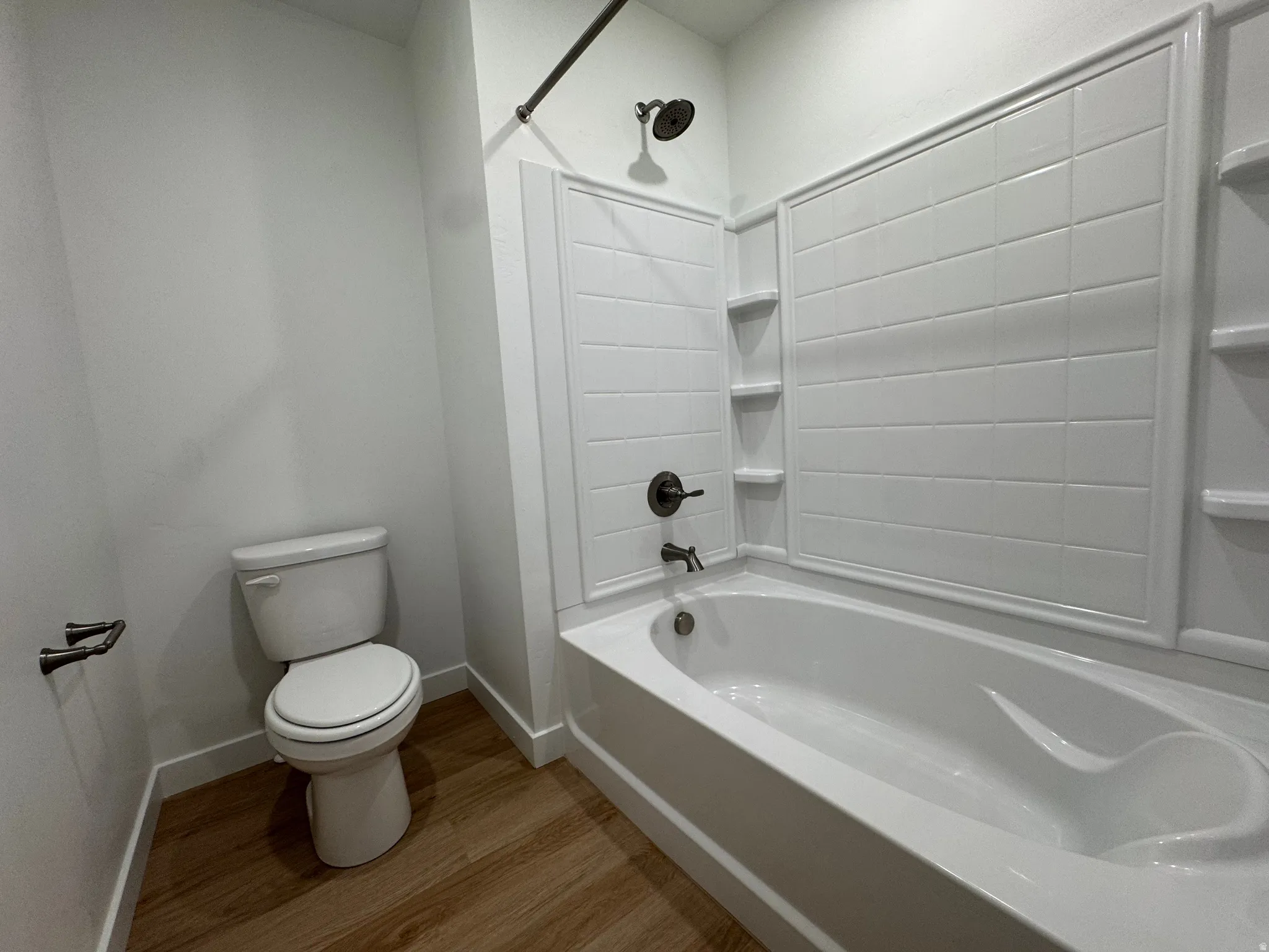Crisp white bathtub and shower surround with integrated shelving, complemented by oil-rubbed bronze fixtures
