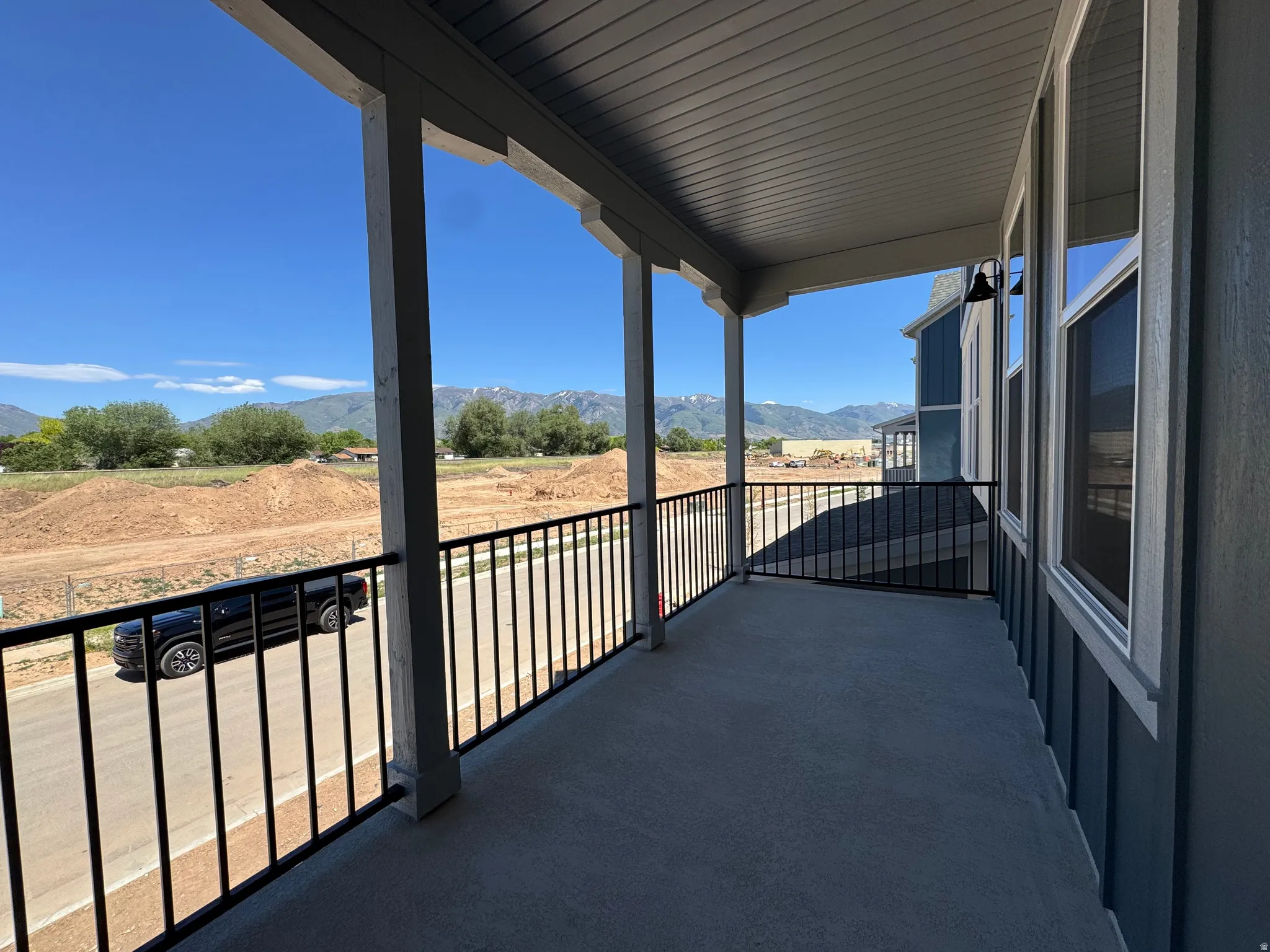Covered balcony featuring a concrete floor, black metal railings, and a blue exterior with white trim