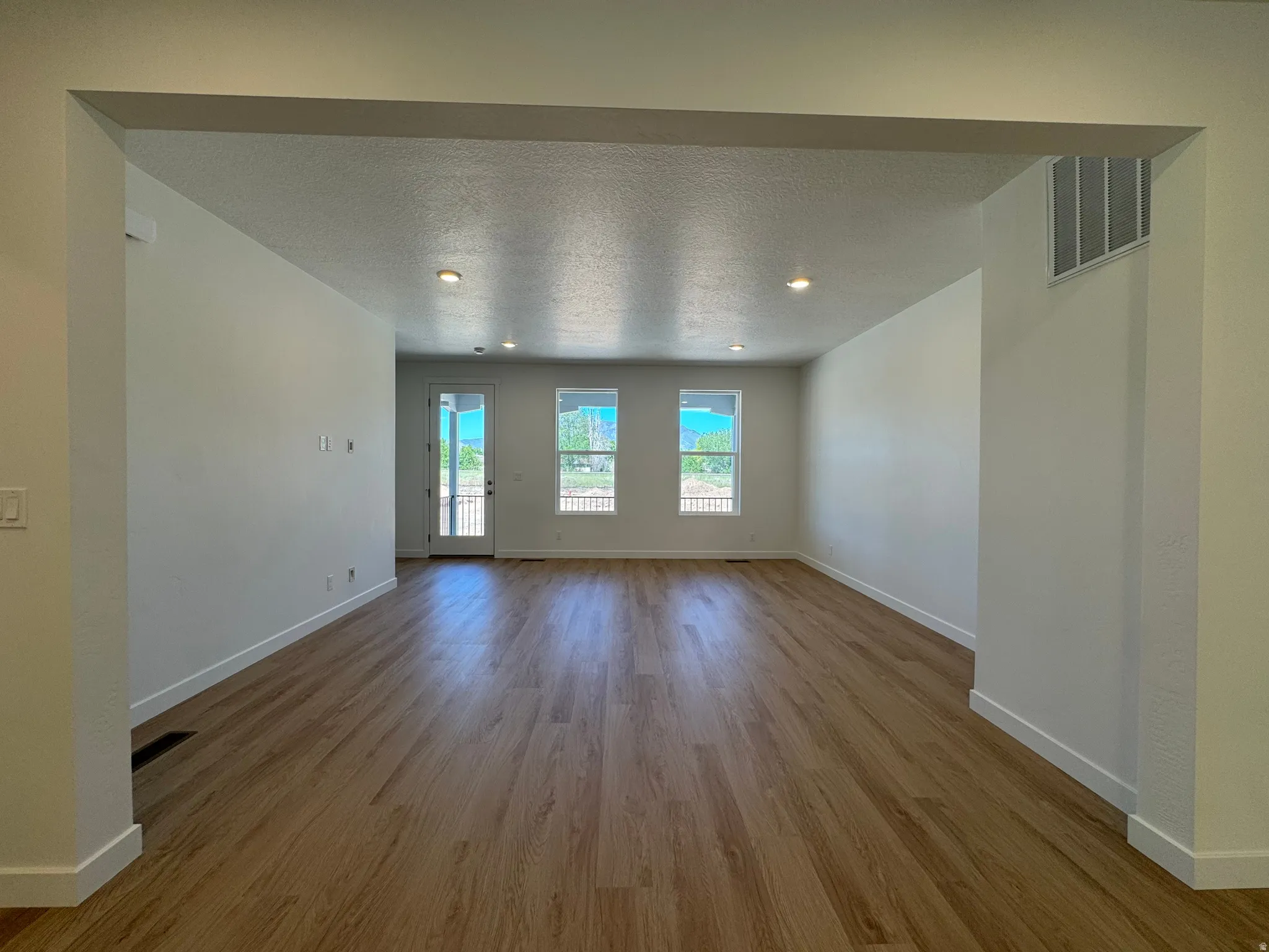 Spacious interior with wood-finish flooring, recessed lighting, and white baseboards