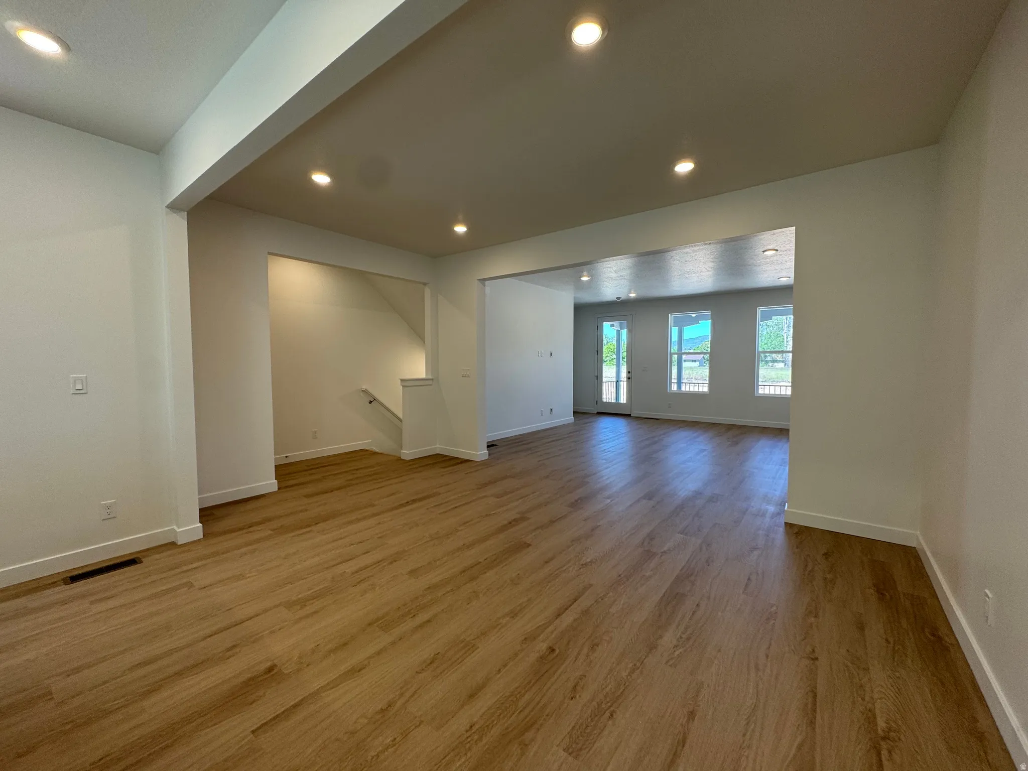 Expansive room featuring wood-finish flooring, recessed lighting, and white baseboards