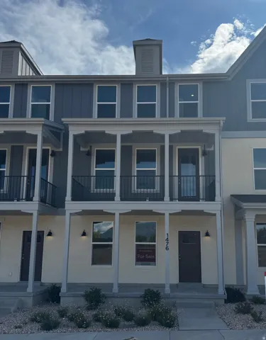 Multi-level townhome-style residence featuring a contemporary facade with light-colored siding and vertical dark blue siding accents