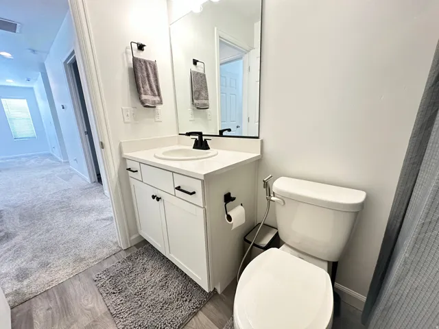 Modern bathroom featuring a white vanity with black hardware, a round sink, and a white countertop