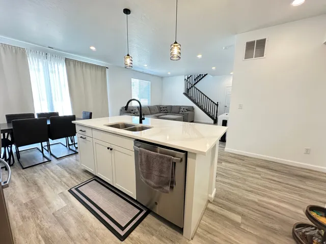 Kitchen island featuring a dual-basin sink with a matte black faucet, integrated dishwasher, and pendant lighting