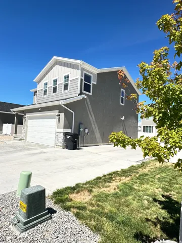 Two-story residence featuring gray stucco siding and light gray horizontal siding on the upper level