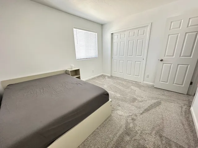 Carpeted room featuring white walls, a window with blinds, and white paneled doors