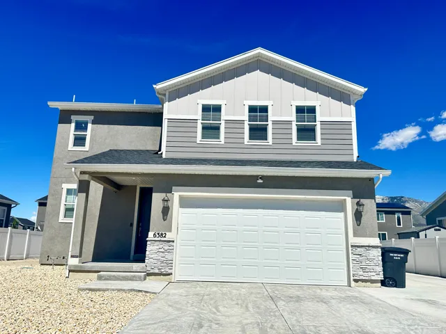Two-story residence featuring a two-car garage, stone veneer accents, and a covered front porch